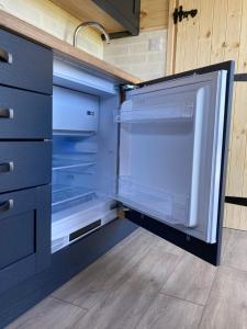 an empty refrigerator with its door open in a kitchen at Shepherd's Huts in Barley Meadow at Spring Hill Farm in Oxford