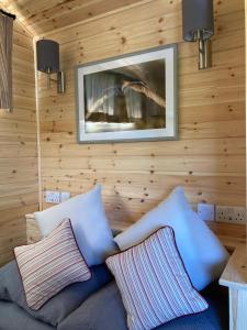 a living room with wooden walls and a couch with pillows at Shepherd's Huts in Barley Meadow at Spring Hill Farm in Oxford