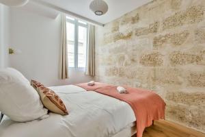a bedroom with a white bed and a brick wall at Nocnoc - Le Balcon de l'Oli 99m2 in Bordeaux