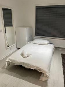 um quarto branco com uma cama e 2 janelas em Belfast Chic: Elegant 2BR Sleeps 5, Prime Location em Belfast