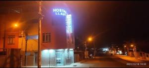 un panneau néon sur le côté d'un bâtiment la nuit dans l'établissement HOSTAL LLAUT * *, à Moquegua