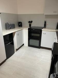 uma cozinha com um fogão preto e armários brancos em Belfast Chic: Elegant 2BR Sleeps 5, Prime Location em Belfast