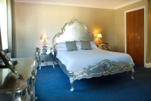 Woodbury Park Hotel & Spa في إكسيتير: غرفة نوم مع سرير أبيض كبير مع سجادة زرقاء