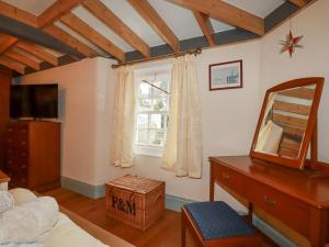 een slaapkamer met een spiegel, een dressoir en een raam bij Mill Cottage in Liskeard