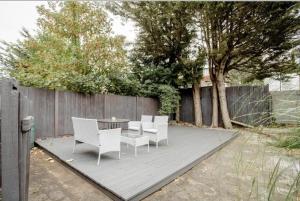 a patio with white chairs and a table and a fence at London comfy doubles in London