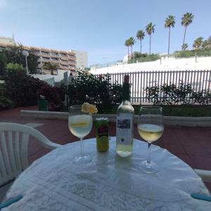 twee glazen witte wijn en een fles op een tafel bij Relax Playa Ingles in Playa del Inglés