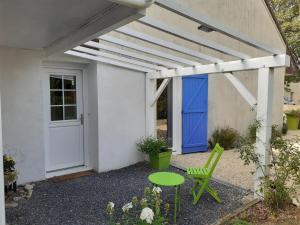 a white house with a blue door and a green table at Les Oiseaux chambre d'hôtes in Saint-Florent-sur-Cher