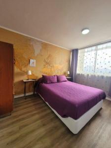 ein Schlafzimmer mit einem großen Bett mit violetter Bettwäsche in der Unterkunft ChileRuca Departamentos Amoblados in Santiago