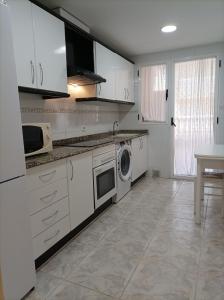 Una cocina con gabinetes blancos y lavadora. en Almar Collection Cullera Bahía Park, en Cullera