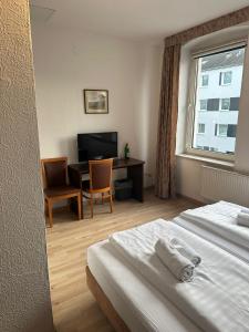 a hotel room with a bed and a desk and a window at Hotel Sonnenschein nähe Messe und Flughafen in Düsseldorf