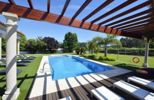 a swimming pool in a backyard with a wooden pergola at Villa 320 in Barcelos