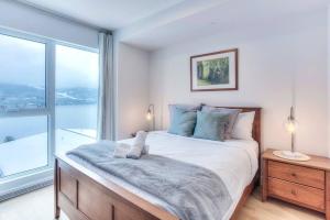 モントランブランにあるSerenity by the Slopes: Tremblant Waterfront Condoの大きなベッドと大きな窓のある寝室