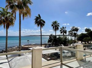 a view of the beach and palm trees from a balcony at Arcadia in Cala Millor