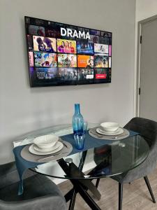 a glass table with two chairs and a tv on the wall at Barn Conversion, Town Centre, Brand new, Beautiful designed, light, fresh and spacious, Secure parking option, Netflix TV ready, Wifi in Wellingborough