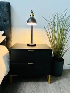 a black dresser with a lamp on it next to a bed at Barn Conversion, Town Centre, Brand new, Beautiful designed, light, fresh and spacious, Secure parking option, Netflix TV ready, Wifi in Wellingborough