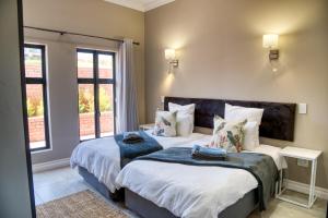 a bedroom with two beds and two windows at Highland Gate Eagles Breeze in Dullstroom