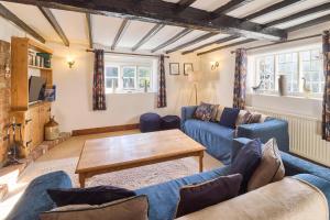 Host & Stay - Bere Cottage في كانتربيري: غرفة معيشة مع أرائك زرقاء وطاولة خشبية