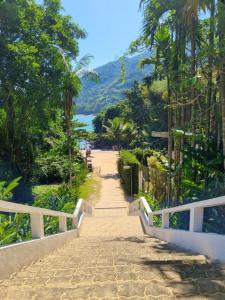 a path leading to a beach with trees and a mountain at Pousada Mar Suites in Ubatuba
