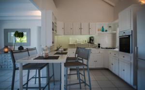 a kitchen with white cabinets and a table and chairs at Saint Barth Villa 2 in Saint-Jean