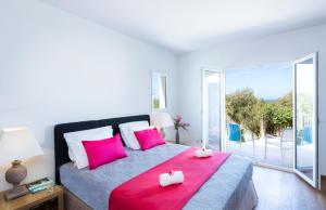 a bedroom with a bed with pink pillows and a balcony at Villa Mare in Corbara