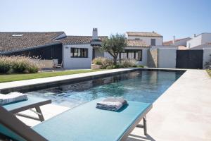 ein Pool mit einer blauen Bank neben einem Haus in der Unterkunft Villa La Saliere in Saint-Clément-des-Baleines