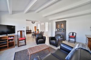 ein Wohnzimmer mit einem Sofa, Stühlen und einem TV in der Unterkunft Villa La Saliere in Saint-Clément-des-Baleines