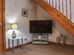 a living room with a flat screen tv and a staircase at Oak Tree Cottage in Brierfield