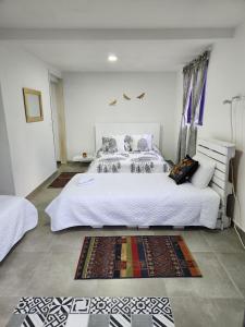 a bedroom with a large white bed and some rugs at Finca Hostal La Esperanza in Quimbaya