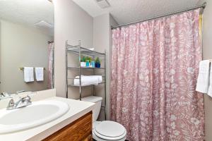 La salle de bains est pourvue d'un rideau de douche rose et d'un lavabo. dans l'établissement Oak Haven: 3 King Beds + Fast Wi-Fi + FREE Parking, 