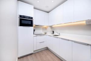 una cucina bianca con armadi bianchi e lavandino di New Modern 1 Bed Flat Great Location Piccadilly Line a Hounslow