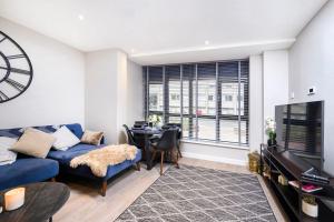 a living room with a blue couch and a table at New Modern 1 Bed Flat Great Location Piccadilly Line in Hounslow