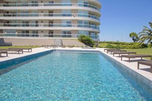 una piscina con bancos y un edificio en Oceana Suites Cruceros III, en Punta del Este