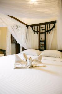 a bed with white sheets and pillows on it at Caravan Serai Amour in Stone Town