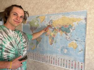 un hombre apuntando a un mapa mundial en una pared en 無料駐車場付き個室 大阪と京都へアクセス 良し無人チェックイン, en Yawata