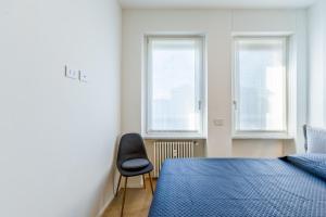 1 dormitorio con 1 cama, 1 silla y 2 ventanas en Appartamenti in Centro - Biancospino Apartments, en Milán