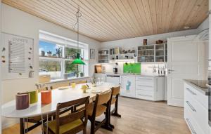 une cuisine avec une table et des chaises et une cuisine avec des placards blancs dans l'établissement Beautiful Home In Faxe Ladeplads With Kitchen, à Fakse Ladeplads