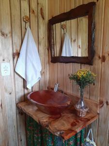 uma casa de banho em madeira com um lavatório e um espelho em Chalé Refúgio das Águas em Urupema
