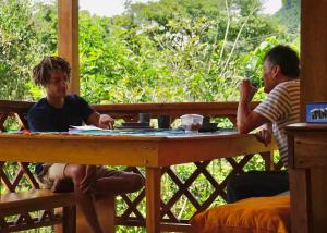 dos hombres sentados en una mesa jugando a un juego de mesa en Inti Mindo Hostel, en Mindo