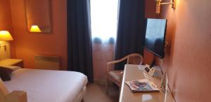 a hotel room with a bed and a table and a window at Logis L'Auberge Bourbonnaise - Vichy sud in Saint-Yorre