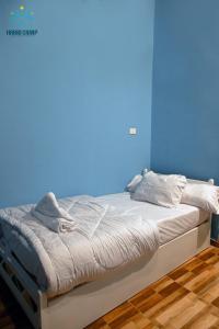 a bed in a room with a blue wall at Habib Camp in Abu Simbel