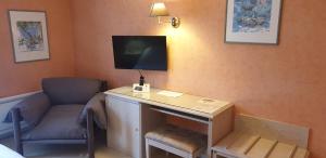 a room with a desk and a chair and a tv at Logis L'Auberge Bourbonnaise in Saint-Yorre