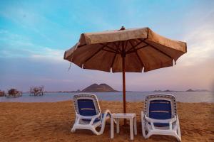 two chairs and an umbrella on the beach at Habib Camp in Abu Simbel