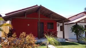 une maison rouge et blanche avec une porte rouge dans l'établissement Chalés do Otto e Karine, à Canoa Quebrada