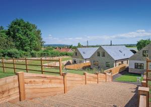 a wooden fence in front of a farm with houses at Windmill Retreat in Middlezoy