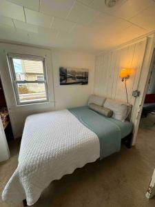a bedroom with a white bed with a window at Beach Cottage on North Beach in Hampton