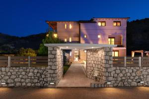 a large house with a stone wall at night at Costa Costa Villa - Luxury villa in Kolymbia