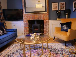 a living room with a glass table and a fireplace at Queens Cottage, Wivenhoe Stylish, Plush, Cosy, Convenient & Quirky, 2x Double Bed Period Cottage PLUS Patio - 9 min walk train, 4 min walk High Street Pubs, Restaurants, Shops in Wivenhoe