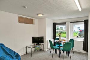 a living room with a table and chairs and a television at Finest Retreats - Atherfield Apartments No 4 - Lawn Side in Paignton