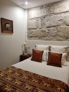 1 dormitorio con cama blanca y pared de piedra en Honey House, en Matosinhos