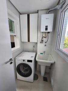 uma pequena casa de banho com uma máquina de lavar roupa e um lavatório em Lindo! Novo ! Perto do Consulado Americano e Shopping! em Porto Alegre